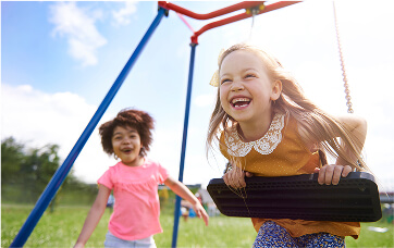 Duas crianças sorrindo brincando em um balanço